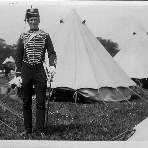 soldier standing in front of a camp of tents