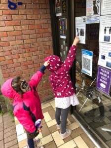 2 children pointing at the museum's spooky shop trail in a shop window