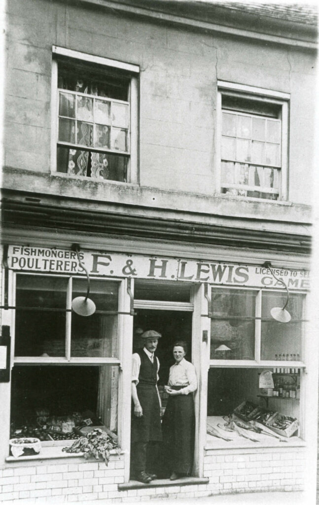 Lewis's shop with a man and woman standing in the doorway. Fish is in the window display