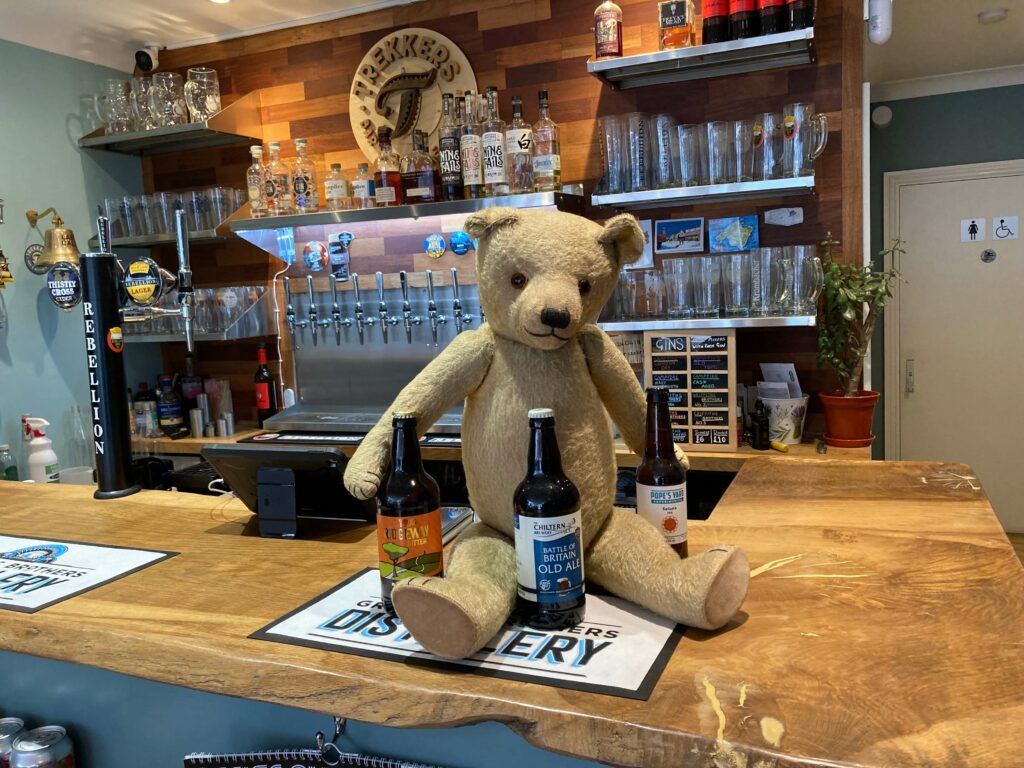 Teddy at the bar with three bottles of ale/bitter next to them