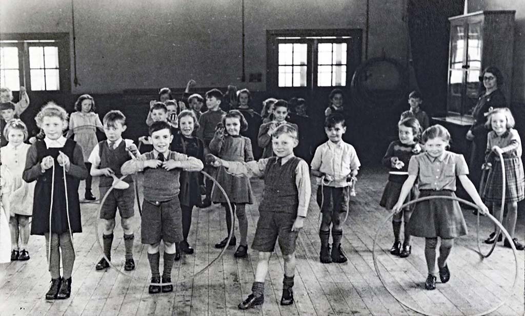 Children playing inside a school hall with hoops and ropes