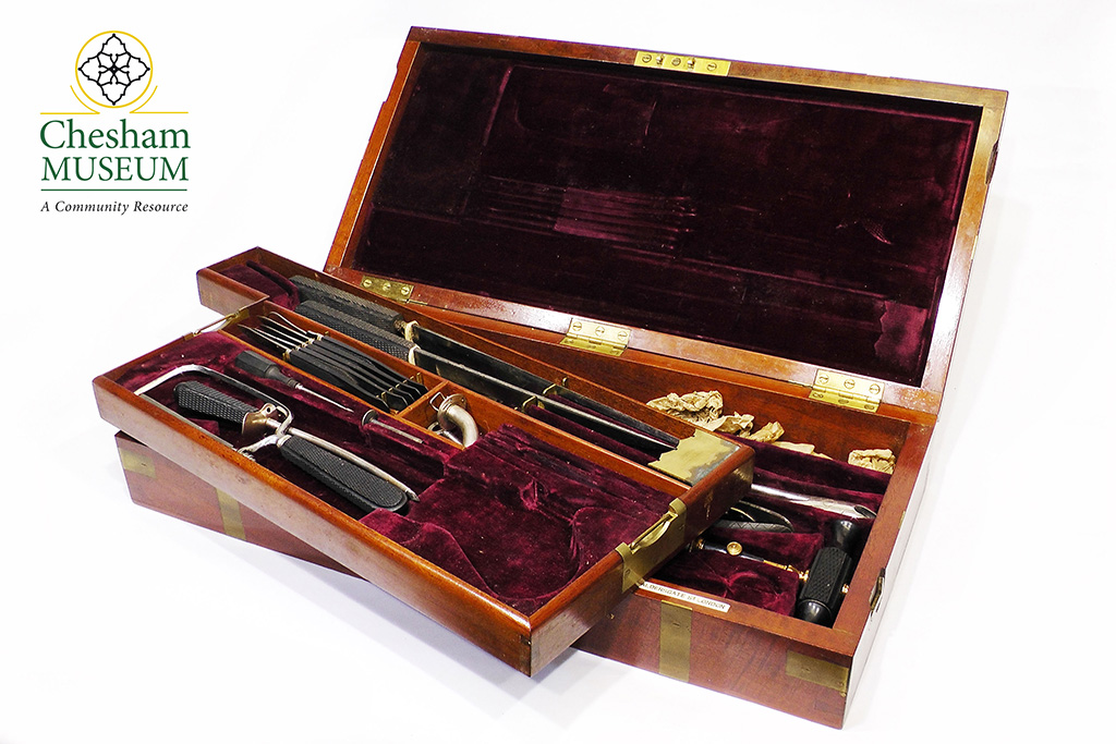 A mahogany medical case with a removable middle section. It is covered inside with a soft, burgundy coloured material and has medical instruments inside.