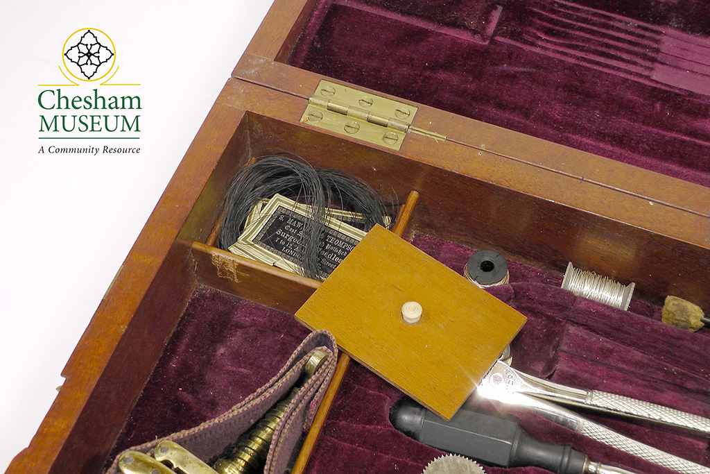 A close up of inside the equipment box showing some instruments, some thread and the purple lining material