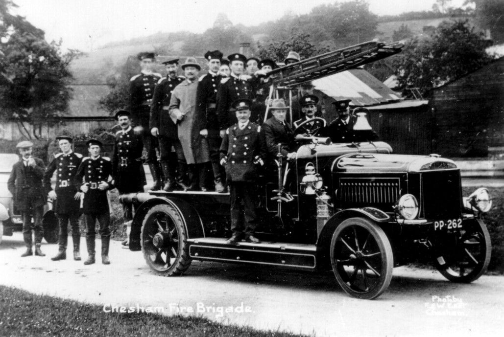 Black and white photo of a fire engine with men standing on top