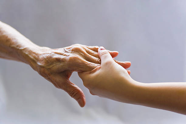 An older person and younger person hands touching