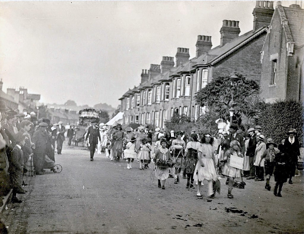 Children, some in costumes, parading down the street