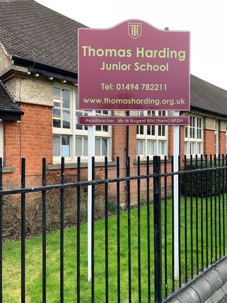 Photo of a sign that says Thomas Harding Junior School, with the school shown in the background