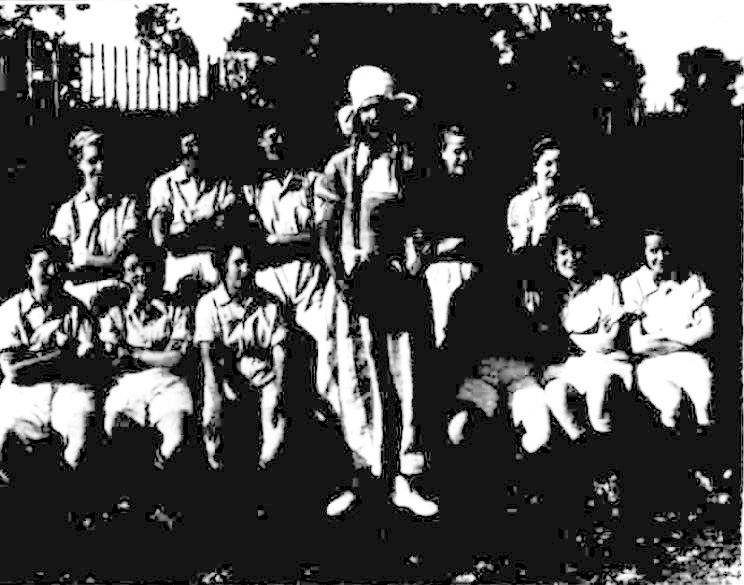 A black and white photo of Royal Bucks Laundry football team. The photo, of low quality, shows the team with some seated and some standing behind them. There is a women standing in the middle of the seated team members