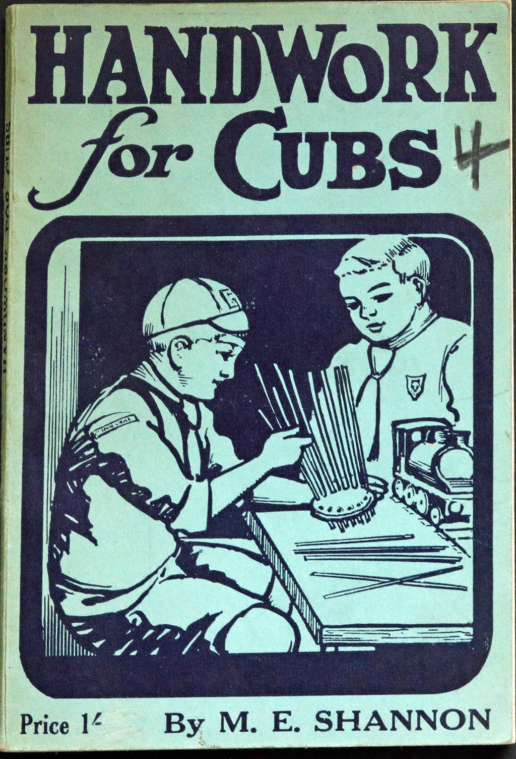 Handwork for Cubs front cover. Author is M E Shannon. The illustration on the cover shows two boys in cubs uniforms making something with long sticks.