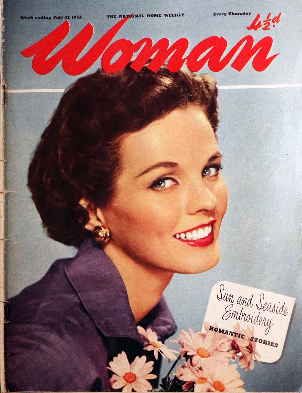Front page of Woman magazine. A woman looks at the camera and smiles. She is holding some flowers.