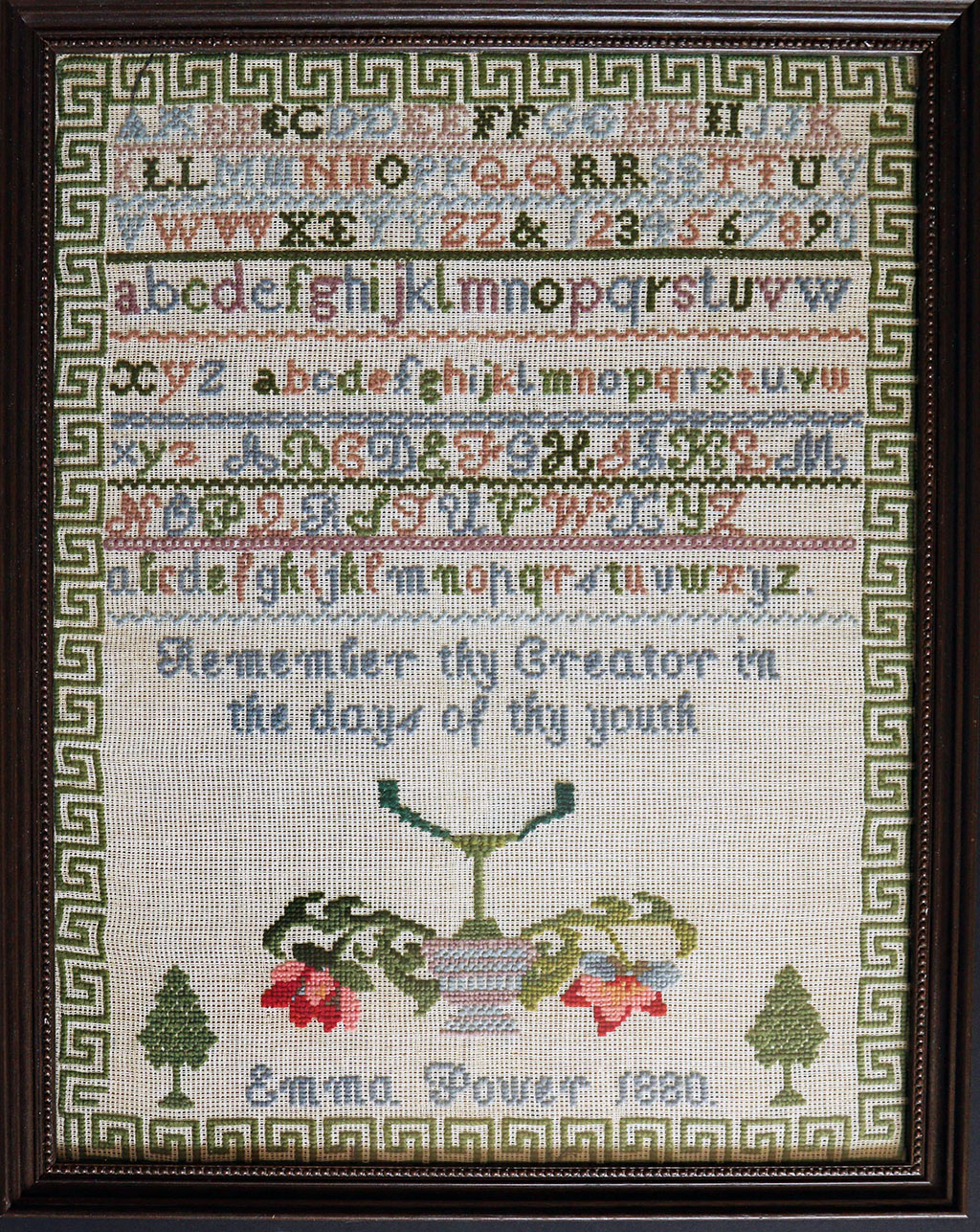 Example of cross stitch showing the letters of the alphabet and a sentence saying Remember they Creator in the days of thy youth. The name Emma Power and date 1880 is shown.
