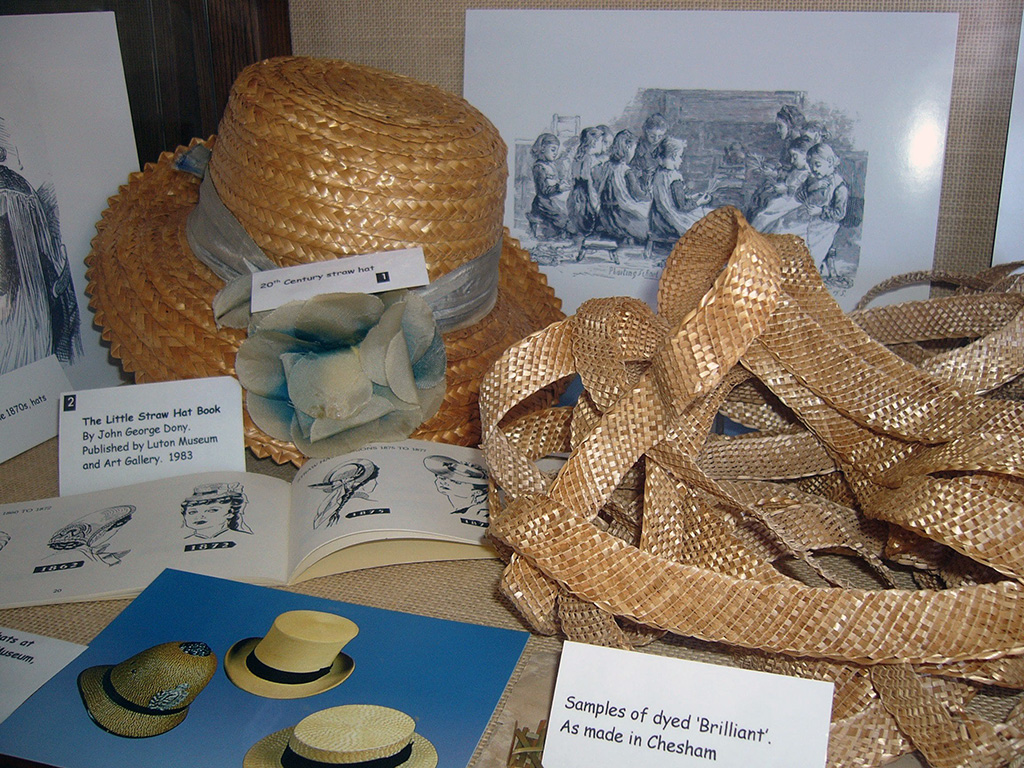 Examples of straw plait, including a 20th century hat, straw hat book and samples of dyed 'brilliant'