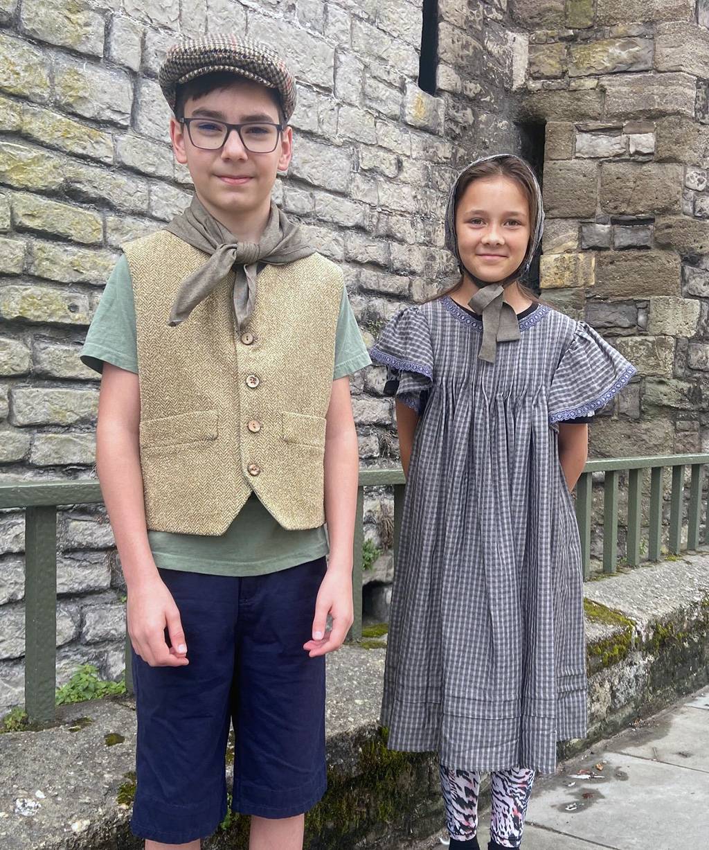 Two children dressed in clothing that poor people would have worn in Victorian times.