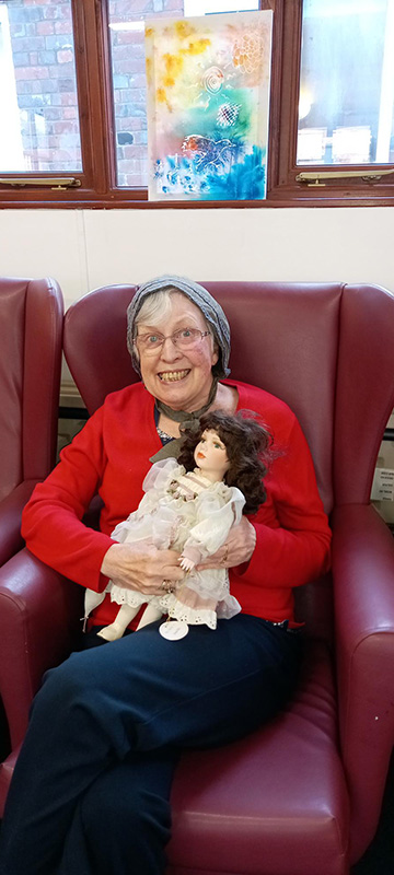 Older lady sitting with a doll
