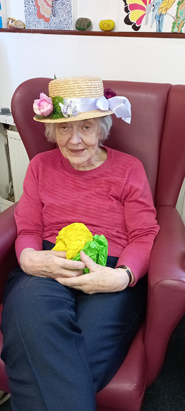 Older lady wearing a hat with a yellow and green object on her lap
